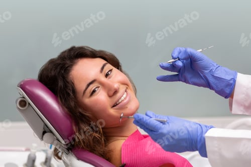 Preview: Portrait of smiling girl looking at camera sitting in dental clinic chair.