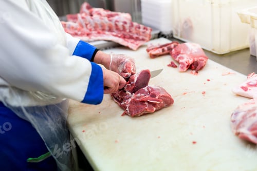 Preview: Closeup of the hands of a butcher cutting slices of raw meat off