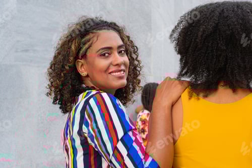 Preview: Cheerful woman walking down the street on the arm of her best friend