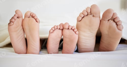 Preview: Shot of a family laying barefoot on a bed at home
