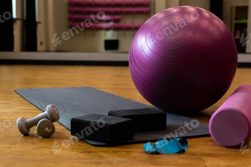 Preview: Set of sports equipment with fitness ball and yoga mat in the gym on the floor.