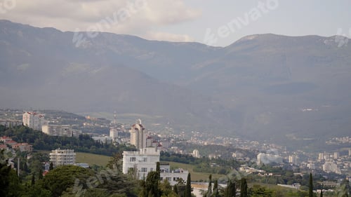 Preview: Fog over the city. Action. Mountains with fields and small houses and green forests above a white