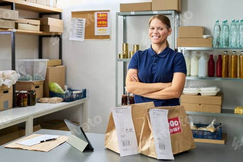 Preview: Caucasian Young Adult Woman Smiling While Preparing Food Delivery Orders