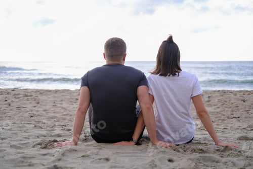 Preview: Young couple sitting together on beach