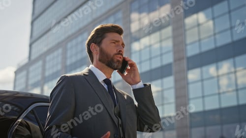 Preview: Worried ceo speaking smartphone near luxury car at sunny street close up.