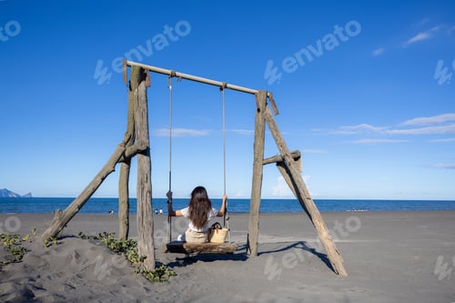 Preview: Woma sit on the swing on stone beach