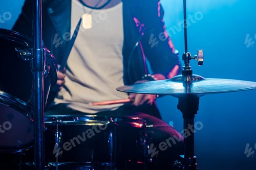 Preview: cropped image of male musician playing drums during rock concert on stage with smoke and dramatic