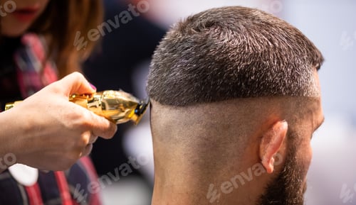 Preview: Barber woman cutting client hair to perfect shape using professional trimmer, close up view