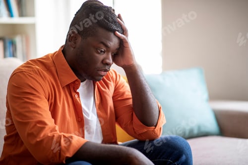 Preview: Shocked chubby black guy sitting alone on couch at home