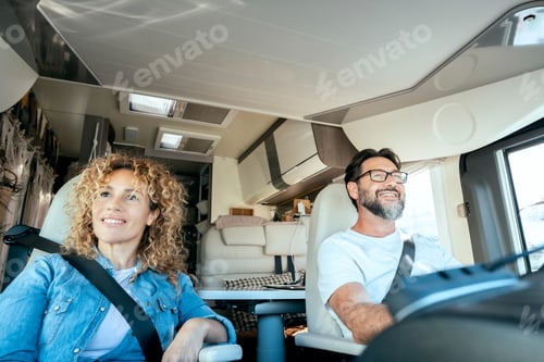 Preview: Man driving camper smiles while driving with his wife company. Concept of travel,