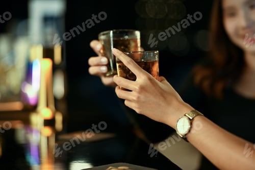 Preview: Two woman hands toasting with drinks at the modern bar.