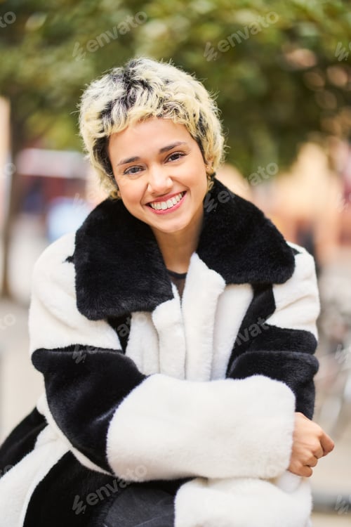 Preview: Young woman smiling in black and white fur coat outdoors