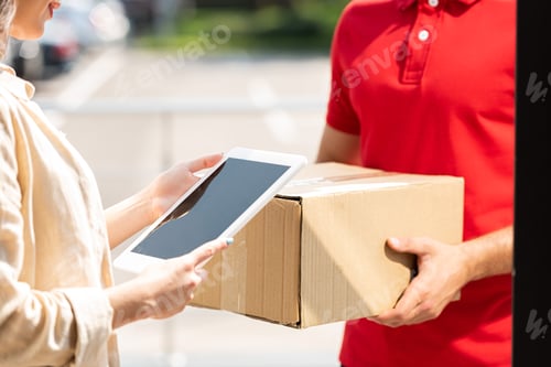 Preview: cropped view of delivery man holding box near woman with digital tablet