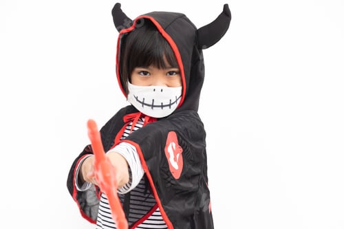 Preview: Asian little girl in a Halloween costume in a medical mask .