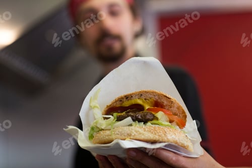 Preview: Young man serving hamburger from fast food van