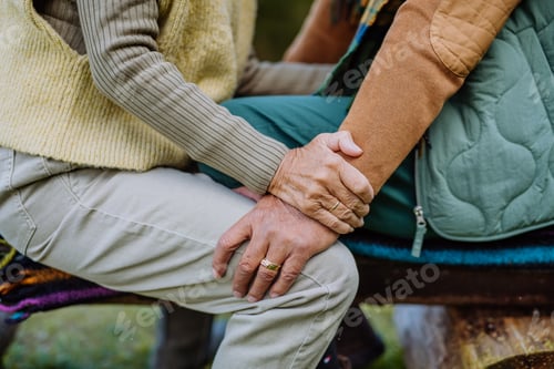 Preview: Mid section of senior couple sitting on bench and hugging each other.