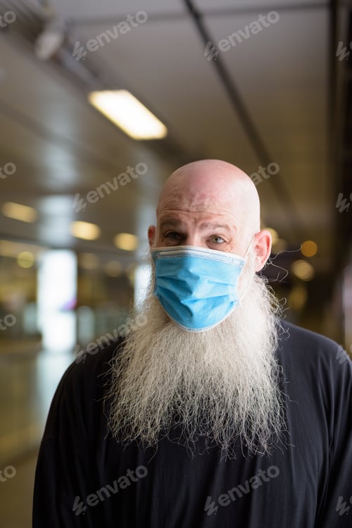 Preview: Face of mature bald bearded man with mask social distancing at the subway train station