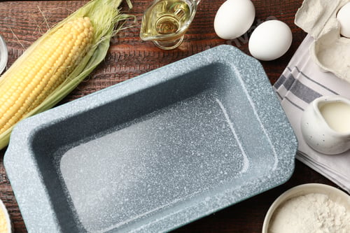 Preview: Baking dish and different ingredients for corn bread on wooden table, flat lay. Space for text