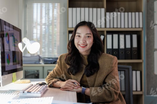 Preview: Asian businesswoman smiling while working at office desk