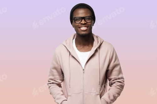 Preview: Portrait of smiling handsome african american guy in pink hoodie standing isolated on purple