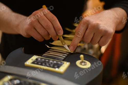 Preview: Guitar in repair service shop with a hands of a guitar luthier which fixes it