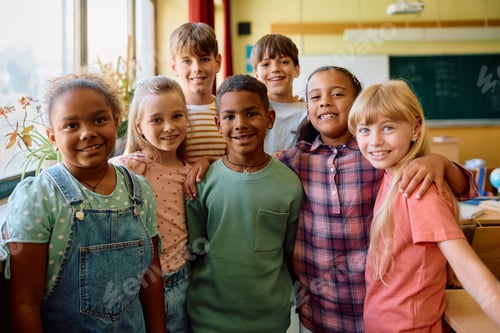 Preview: Group of happy elementary school classmates in the classroom looking at camera.