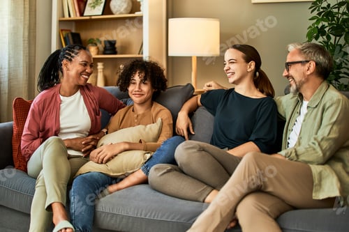 Preview: A happy family of different races and ages sitting together on a couch and talking.