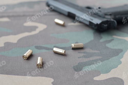 Preview: 9mm bullets and pistol lie on camouflage green fabric