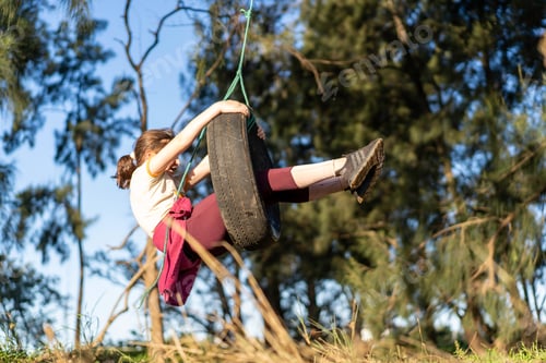 Preview: Young Girl child playing on tire tyre Swing hanging from a tree, having the time of her life.