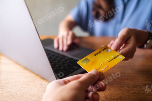Preview: A woman receiving a credit card from customer while using laptop computer for payment
