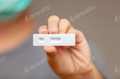 Preview: Man hand holding Covid 19 positive result self test.