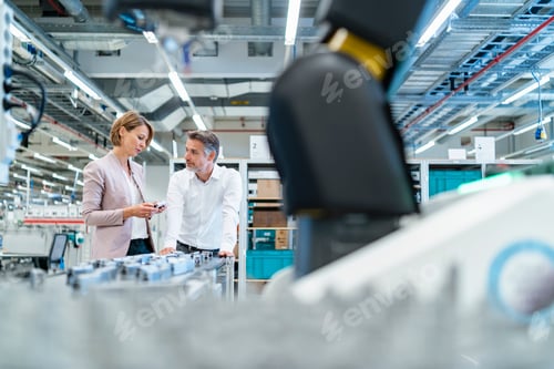 Preview: Businessman and businesswoman talking in a modern factory hall