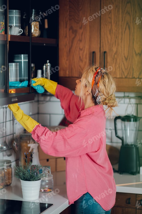 Preview: Woman organizing kitchen cabinets while cleaning