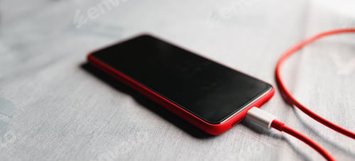 Preview: Mobile smartphone charging battery on office table close-up. Technology, multiple sharing