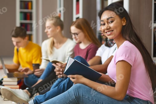 Preview: Group of diverse classmates sitting on floor at library
