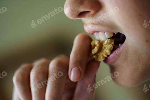Preview: Crop anonymous girl eating fresh healthy walnut at home