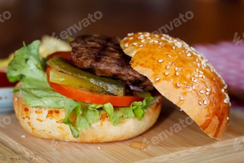 Preview: Closeup of a delicious beef patty burger with golden French fries served atop a freshly-baked bun