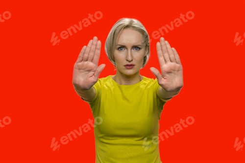 Preview: Young woman showing stop gesture with both hands.