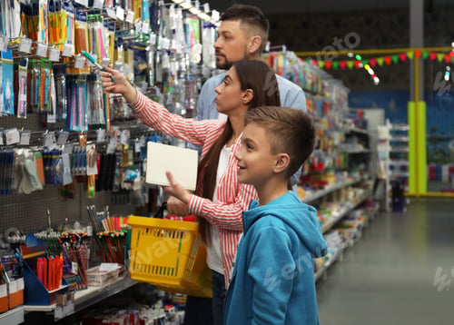 Preview: Family with little boy choosing school stationery in supermarket