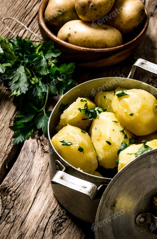 Preview: Boiled potatoes with herbs on wooden table .