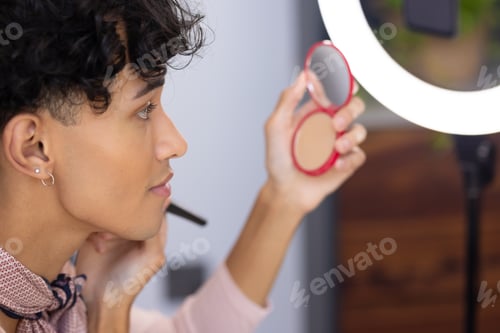 Preview: Applying makeup, transgender transgender woman using compact mirror and brush at home