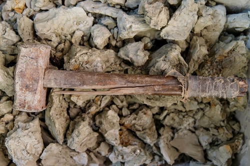 Preview: Old hammer and shattered gray dry stone clay pieces for pottery, top view