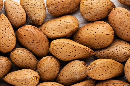 Preview: Group of almond nuts with leaves.Wooden background.