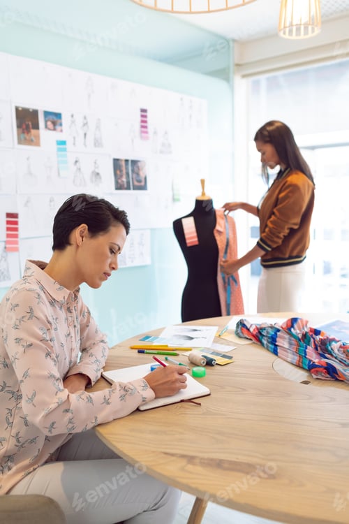 Preview: Attentive mixed race female fashion designers working in a modern office.