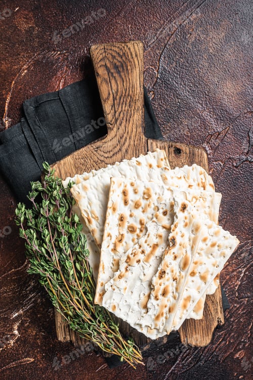 Preview: Happy Passover concept, matzah on a wooden board. Dark background. Top view