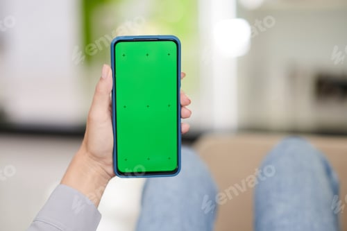 Preview: Hand of young woman holding smartphone with black green screen