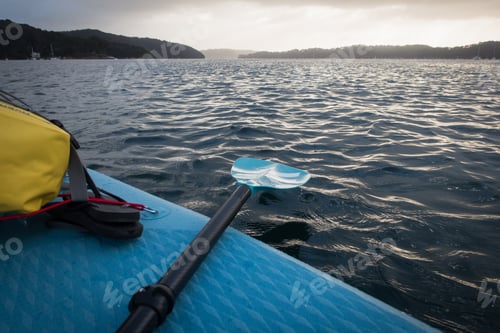Paddle Board with Turquoise Paddle on Rippled Water