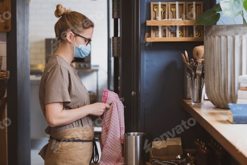 Preview: Blond waitress wearing face mask working in a cafe.