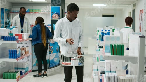 Preview: Young customer checking packs of medicine on shelves