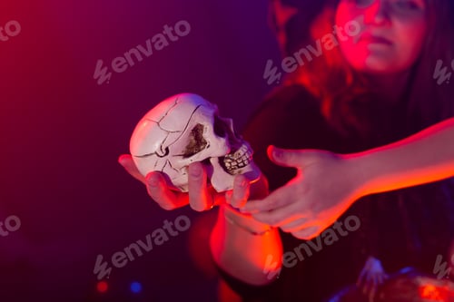 Preview: Halloween witch making magic with scull in halloween night. Magic, holidays and mystic concept.